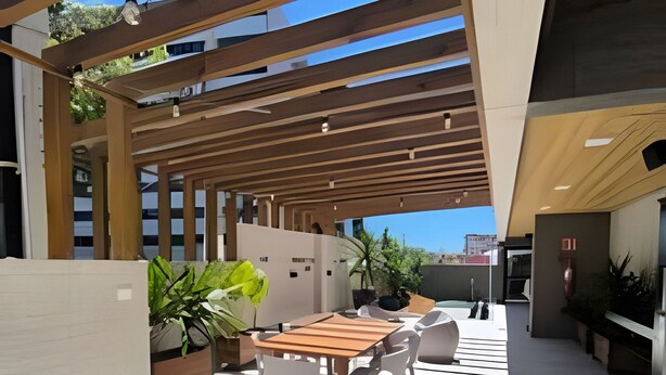 Eine Außenpatio mit einem Holztisch und Stühlen, umgeben von Topfpflanzen und einer Pergola.