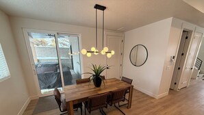 Un coin repas comprenant une table en bois, des chaises, une plante en pot et un luminaire suspendu.