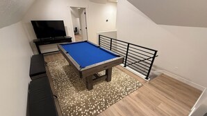 A room with a pool table, a television, and a staircase. - Luxury 5BR Adventure Hub! Pineview, Hiking, Golfing, Biking. Sleeps 12. 4.5 bath (Eden)