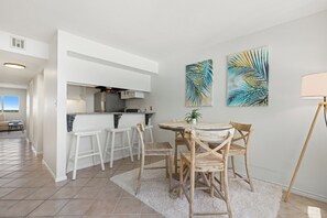 A modern kitchen with white cabinetry and a dining area with wooden chairs and a round table.