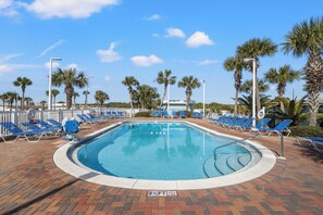 A pool area with blue lounge chairs and palm trees.