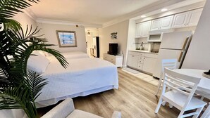 Ein Schlafzimmer mit Bett, Stuhl, Schreibtisch und einer Küchenzeile.