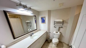 Ein Badezimmer mit Waschbecken, Spiegel, Toilette und Fliesenboden.