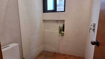 Un baño con ducha, inodoro y una pequeña ventana.