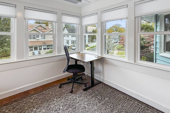 A room with a corner desk, a black office chair, and a patterned floor.