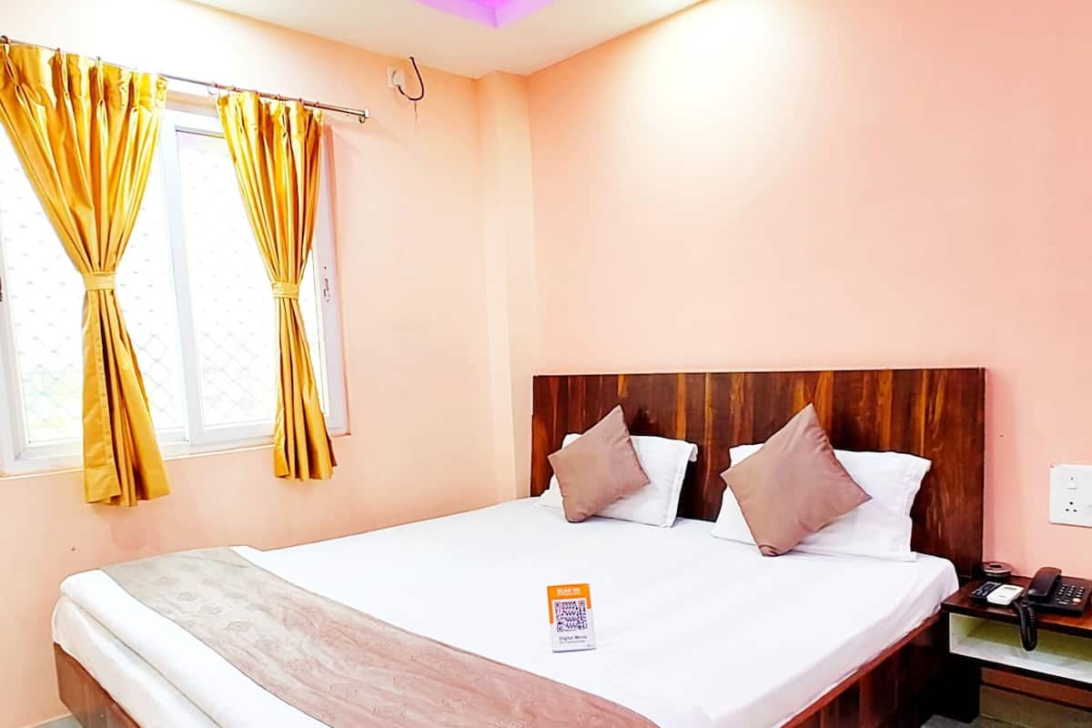 Habitación de hotel con una cama grande, cabecera de madera y una mesita de noche con teléfono.