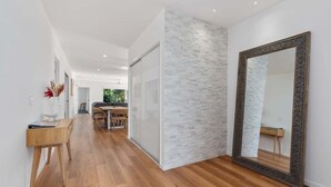 Un pasillo moderno con suelo de madera, pared decorativa de ladrillo blanco y un espejo grande.