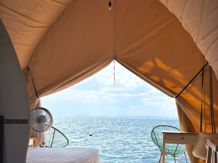 Una tienda de campaña con cama, mesa y silla, con vista al mar.