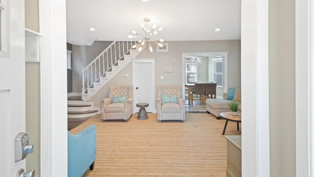 A spacious living room with a high ceiling, a staircase, and a dining area.