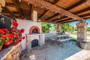 An outdoor patio with a stone oven, wooden table, and benches. - Masseria Santu Lasi With Private Pool & BBQ (Surbo)