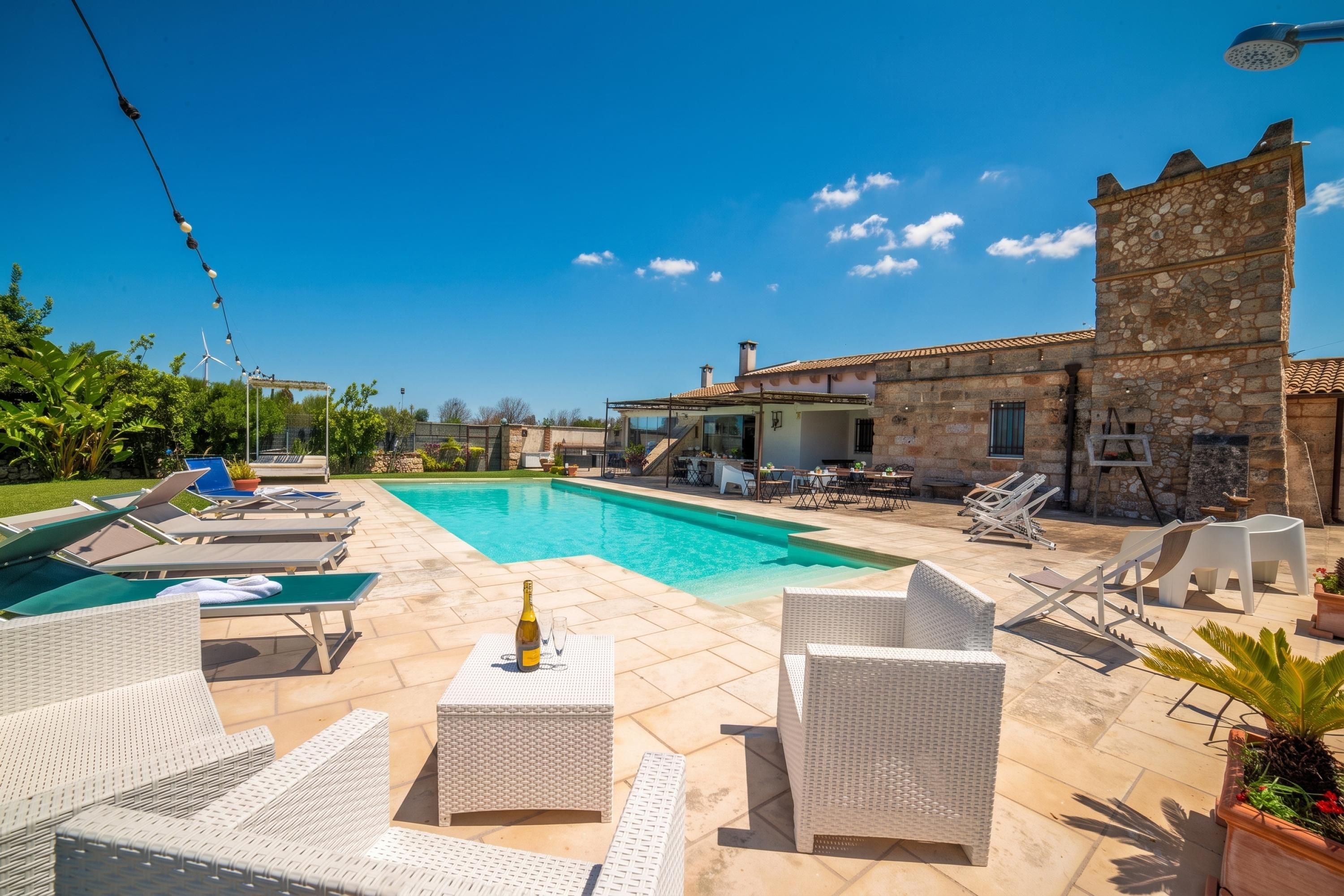 A swimming pool with lounge chairs and a stone building in the background.