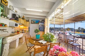 Una cocina con un lavamanos de piedra, armarios de madera y un comedor con mesa y sillas.