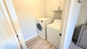 Une buanderie équipée d’un lave-linge et d’un sèche-linge, avec un plancher en bois et un meuble de rangement.