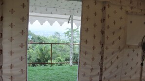 A room with a window overlooking a grassy area and trees. - Billing View Camp and Mud Houses (Jogindarnagar)