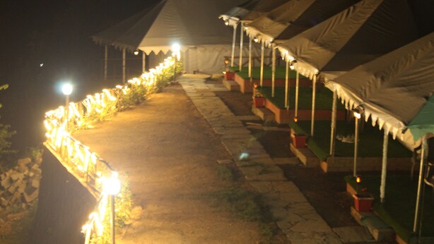 A row of tents with a pathway between them, illuminated by overhead lights. - Billing View Camp and Mud Houses (Jogindarnagar)