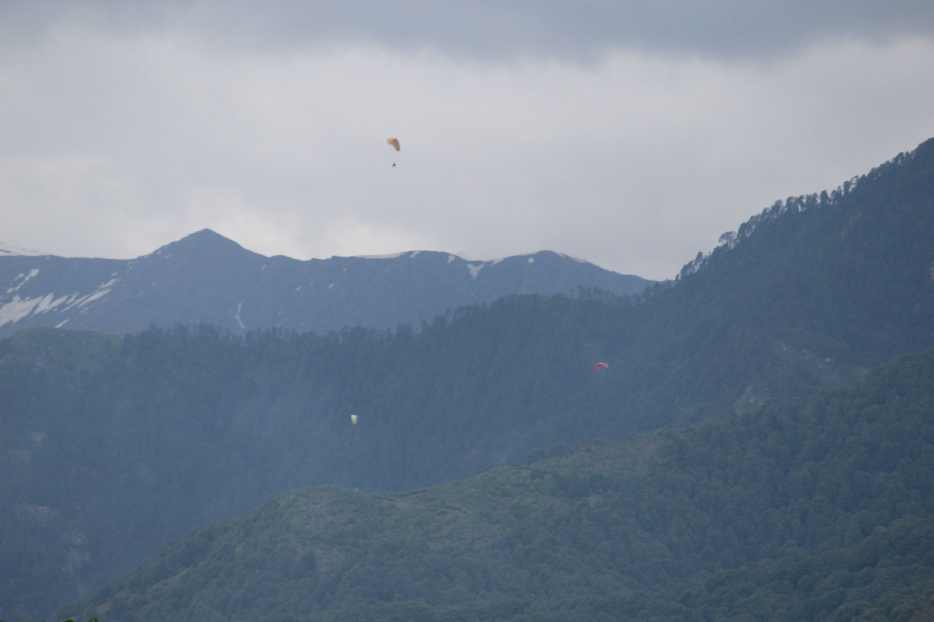 A mountainous landscape with a clear sky and a few kites flying.