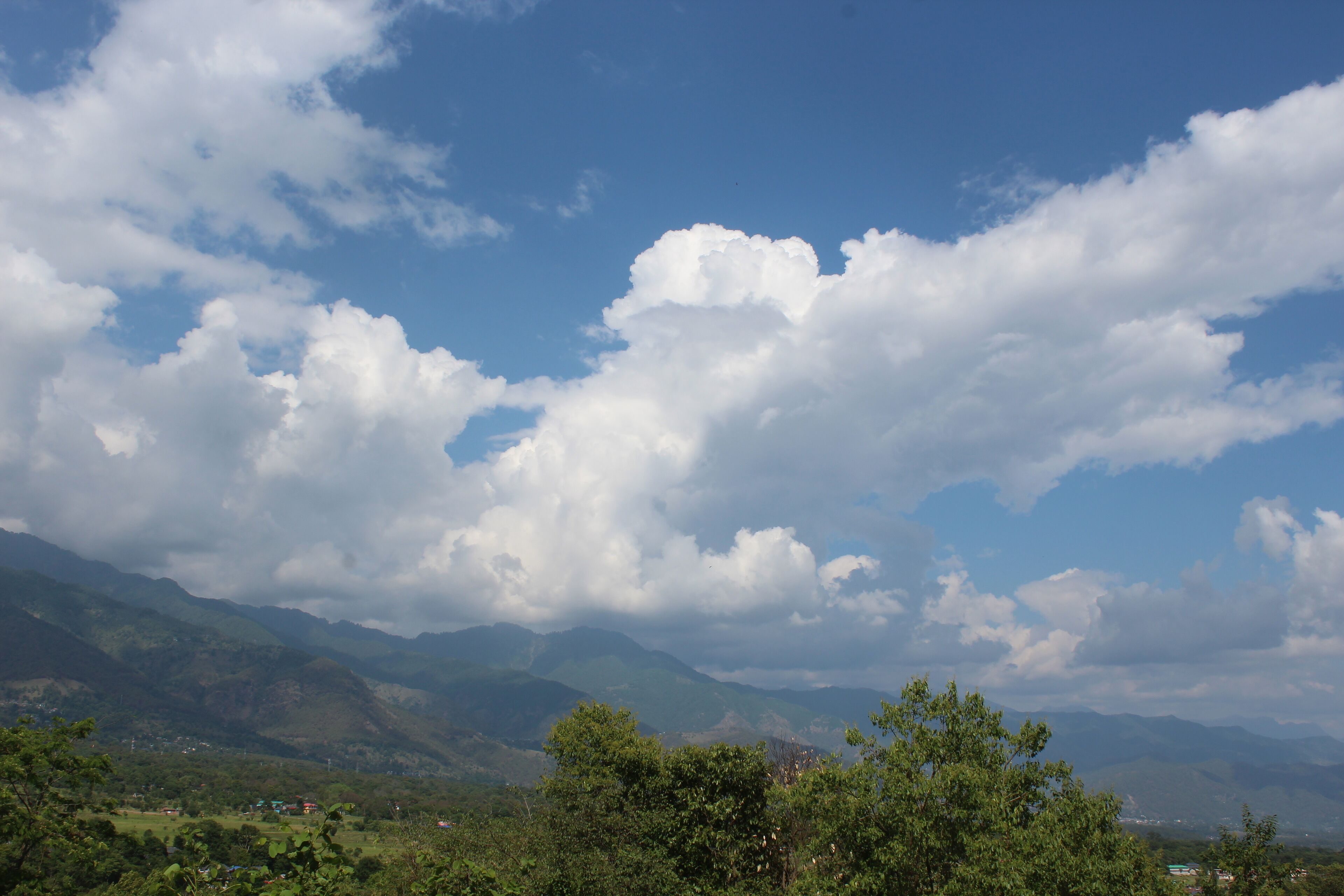 Paisaje montañoso con cielo despejado y nubes dispersas.