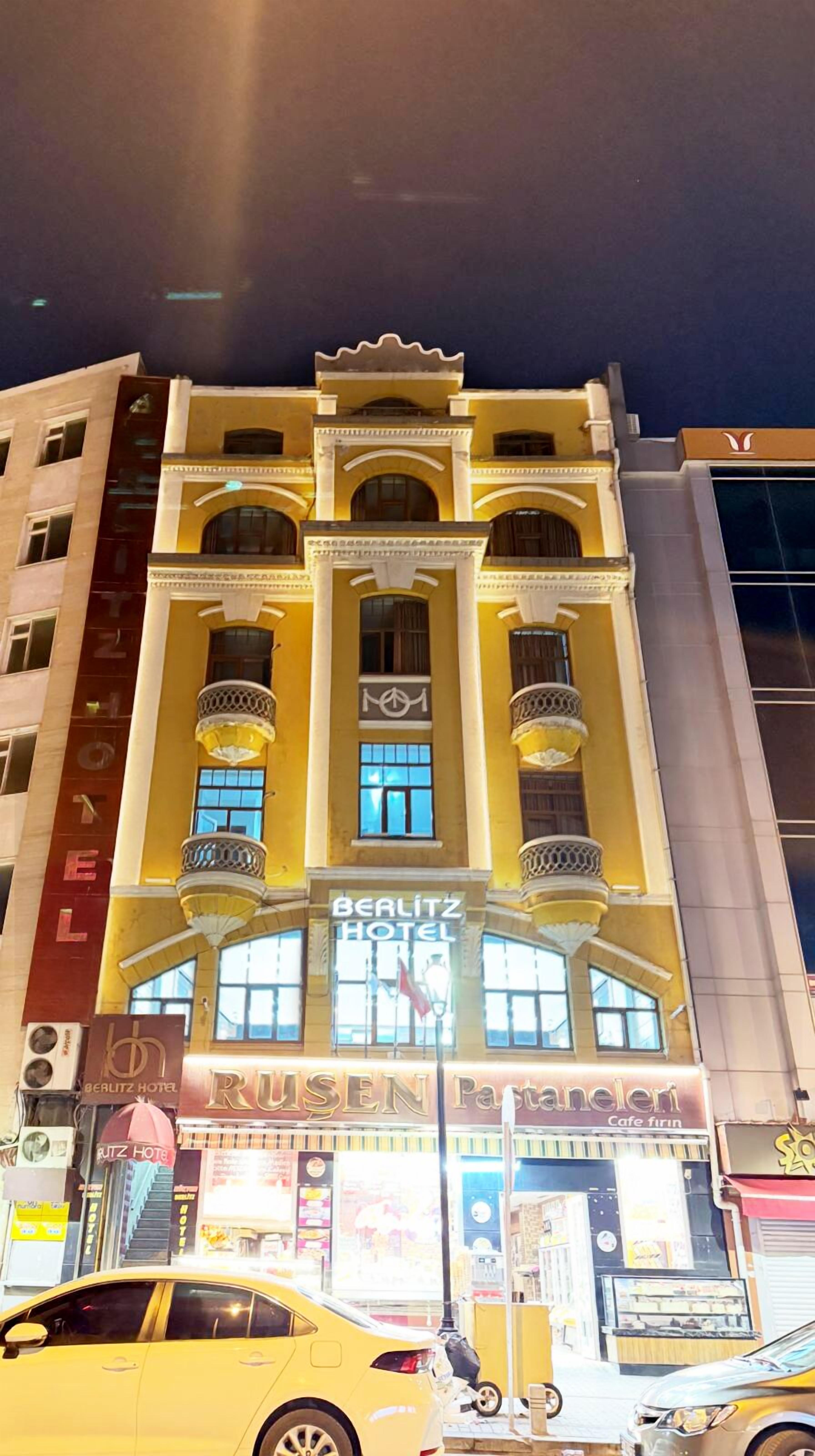 A multi-story hotel with a yellow facade, large windows, and balconies.