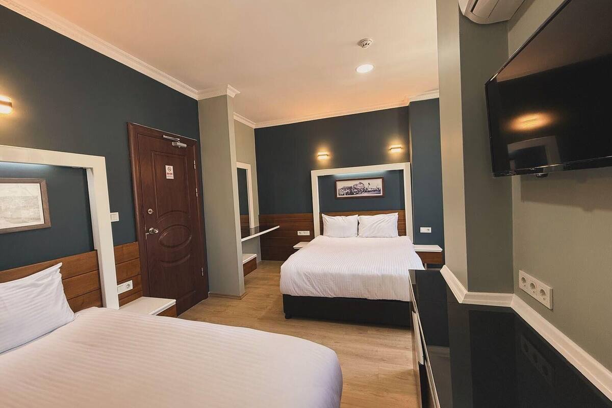 A hotel room with two beds, a TV, and a door with a sign.
