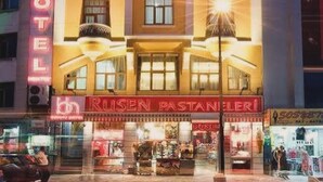 Un hôtel avec une enseigne bien visible portant l’inscription « BERLITZ HOTEL » et, en dessous, une devanture de magasin nommée « RUSEN PASTANERI ».
