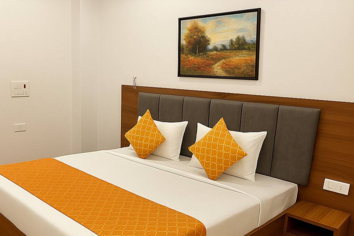 A neatly made bed with a patterned orange bedspread, two matching pillows, and a wooden headboard.