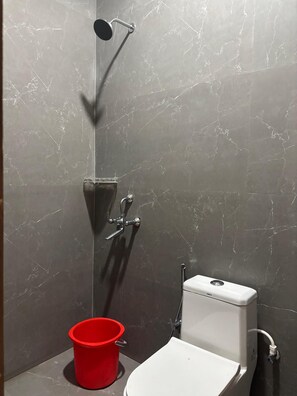 A bathroom with a shower, toilet, and a red bucket. - OnlyStay Surbhi Dham (Vrindavan)