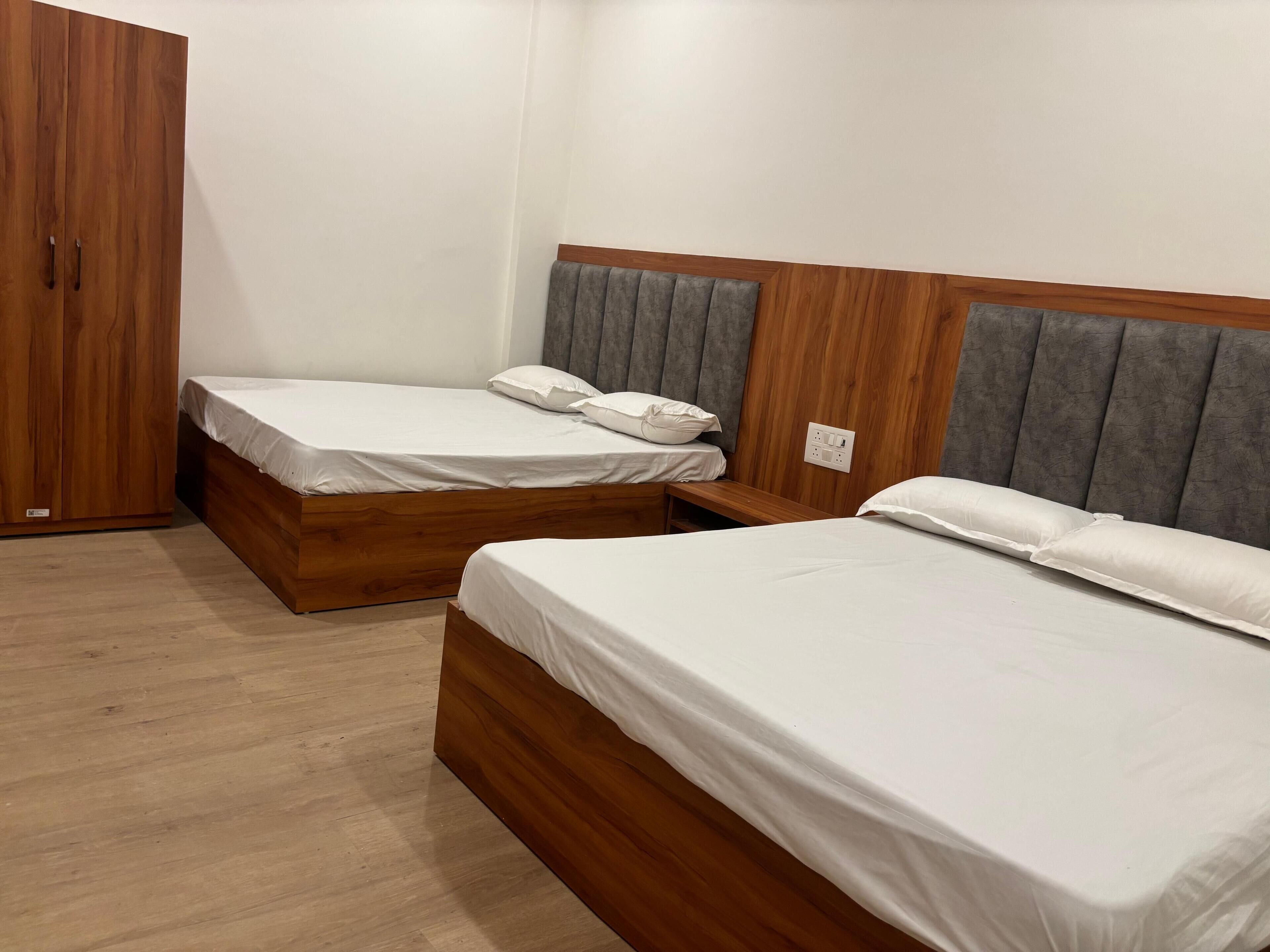 A bedroom with two wooden beds, a wardrobe, and a grey upholstered headboard.