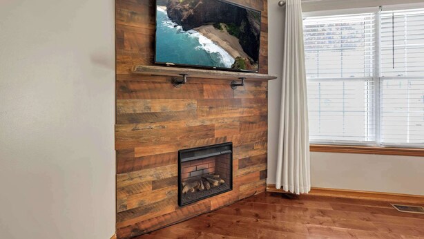 A living room with a wooden wall, a mounted TV, and a fireplace. - Quiet Ranch Retreat for Work Crews & Families Johnstown, OH (Johnstown)