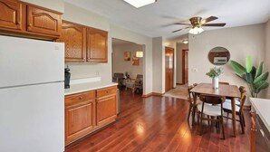 A kitchen with wooden cabinets, a white refrigerator, and a dining area with a wooden table and chairs. - Quiet Ranch Retreat for Work Crews & Families Johnstown, OH (Johnstown)