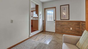 A living room with a sofa, a door leading to a kitchen, and a framed picture on the wall. - Quiet Ranch Retreat for Work Crews & Families Johnstown, OH (Johnstown)
