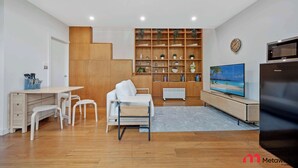 A modern living room with a wooden desk, white sofa, and a TV on a wooden stand. - MetaWiseBnB Stylish Loft Studio with Garden in Seaforth (Seaforth)