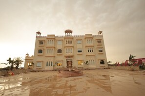 A large, multi-story building with a central courtyard and a fountain. - Agastya Vilas Resort (Sujangarh)