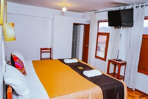 A hotel room with a bed, a TV mounted on the wall, a small table, and a window with curtains. - Mayza Hotel cuzco (Cusco)