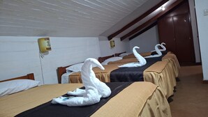 Une chambre d’hôtel avec trois lits, chacun agrémenté d’une serviette en forme de cygne.