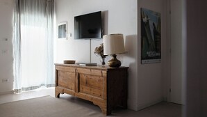 Une pièce avec un meuble en bois, un téléviseur fixé au mur, une lampe et une affiche.