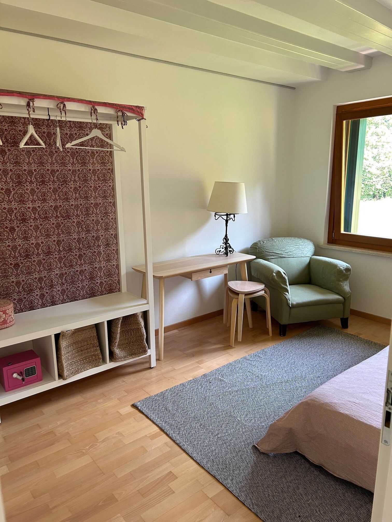 A bedroom with a bed, a desk, a chair, a lamp, and a wardrobe.