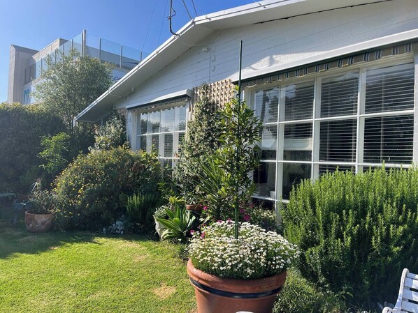Un edificio con amplios ventanales y un jardín cuidado con diversas plantas y flores.