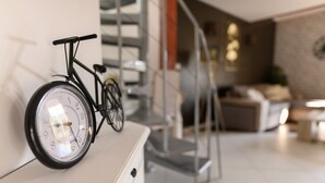 Un intérieur moderne avec un vélo accroché au mur, un escalier et un espace de vie comprenant un canapé et une table basse.