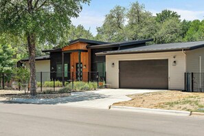 A modern two-story house with a garage, a fenced yard, and a driveway.