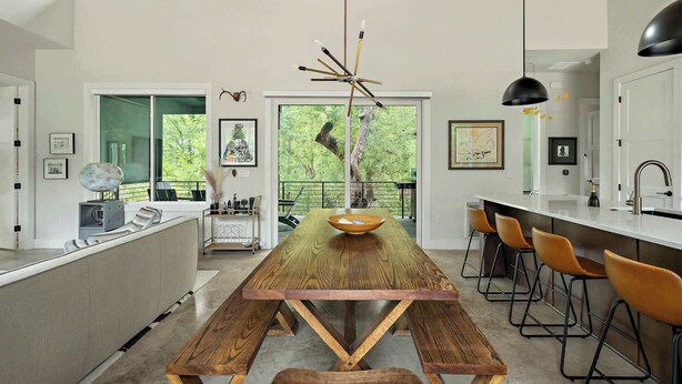 A modern kitchen with a wooden island, bar stools, and a hanging light fixture.