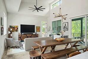 A modern living room with a large TV, wooden furniture, and artwork on the walls. - Stylish East Austin Home | 2BR | BBQ | Near DT ATX (Austin)