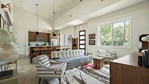 A spacious living area with a sofa, dining table, and kitchen in the background.