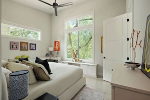 A bedroom with a bed, bedside table, lamp, and artwork on the wall.