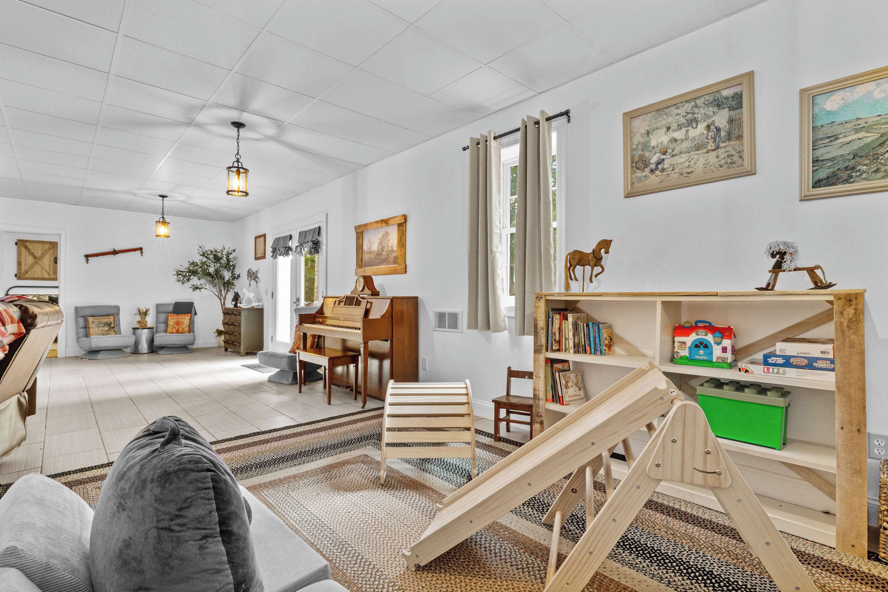 A spacious living room with a piano, a wooden play area, and a bookshelf.