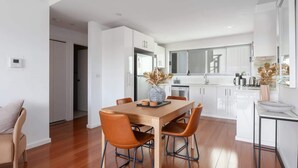 A modern kitchen with white cabinets, a wooden dining table, and two brown chairs.