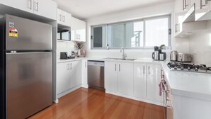 A modern kitchen with white cabinets, stainless steel appliances, and a window providing natural light.