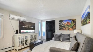 A bedroom with a bed, a TV displaying a welcome message, a cabinet, and a window.