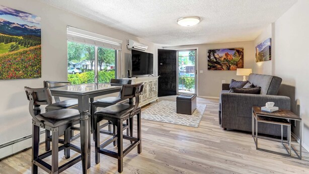 A modern living room with a dining area, a gray sofa, and a TV.