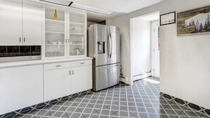 A modern kitchen with white cabinets, a stainless steel refrigerator, and a patterned floor.