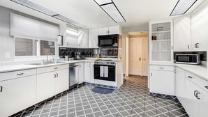 A modern kitchen with white cabinets, a microwave, and a stove.